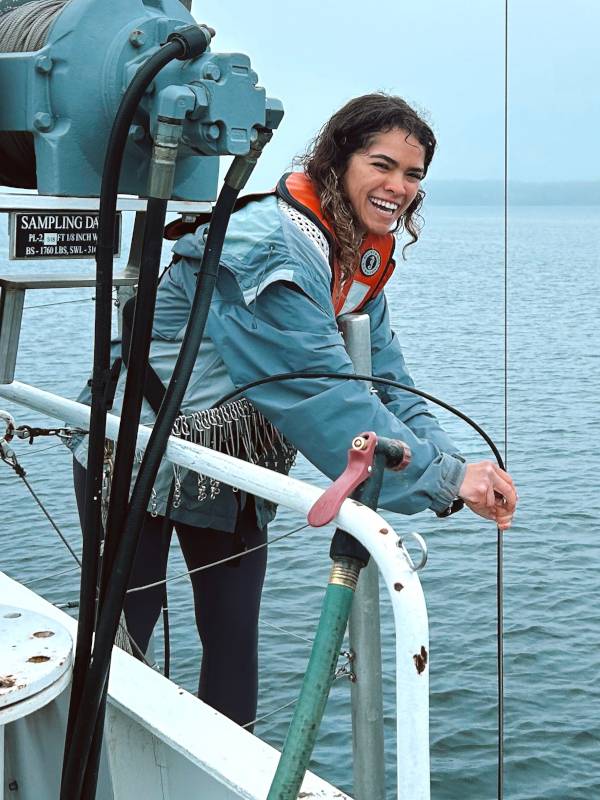 Nicole D'Arienzo holds sampling equipment over the side of the R/V W.G. Jackson